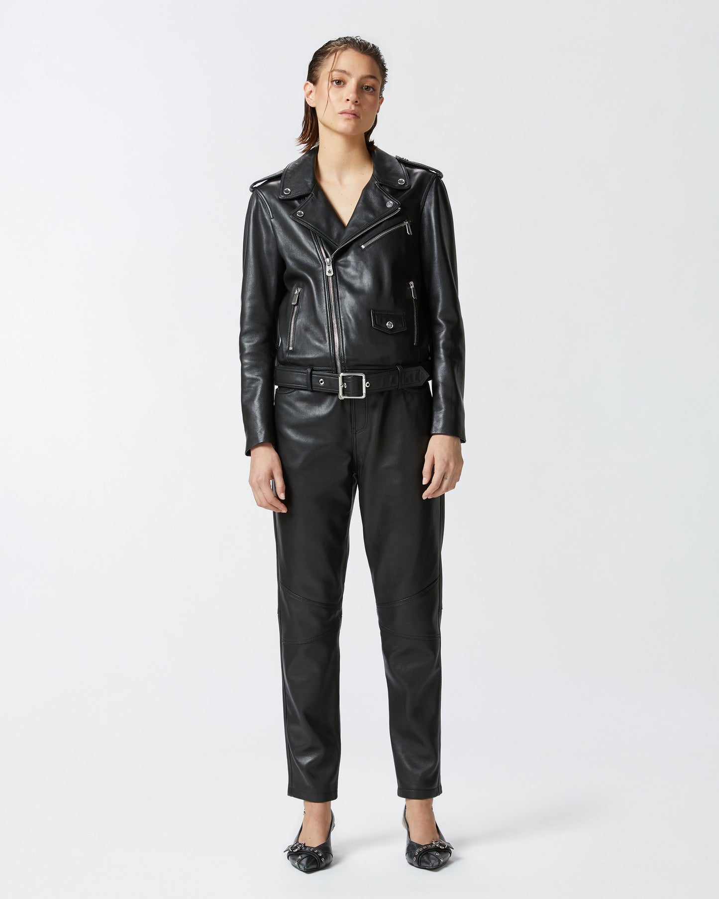 Person wearing a black leather jacket and pants on a white background