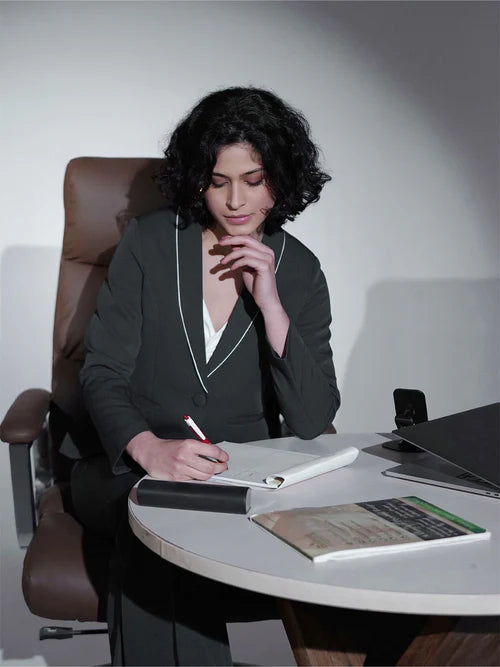 Woman sitting at a desk in an office setting, writing in a notebook.